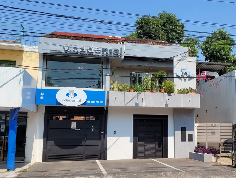 La fachada de Vidadental: el cartel azul con el logo, las letras vidadental arriba y lugares para estacionar al frente